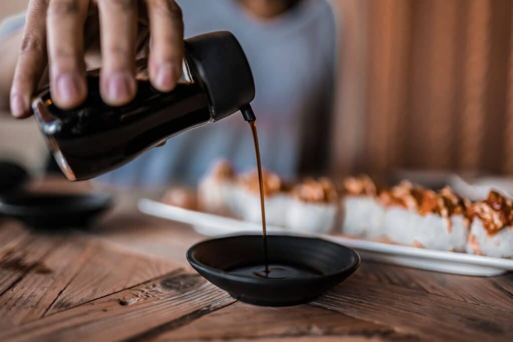 Man hand pouring soy sauce in the small plate