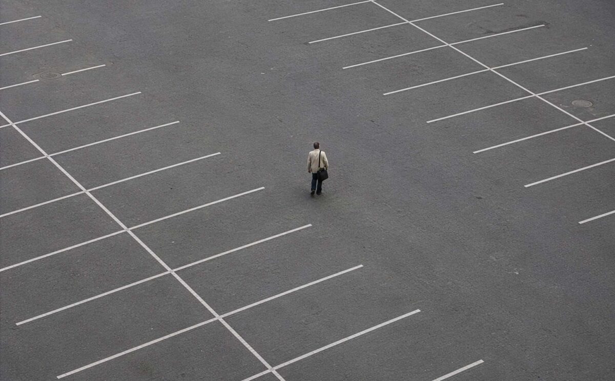 A man standing in the middle of a empty carpark