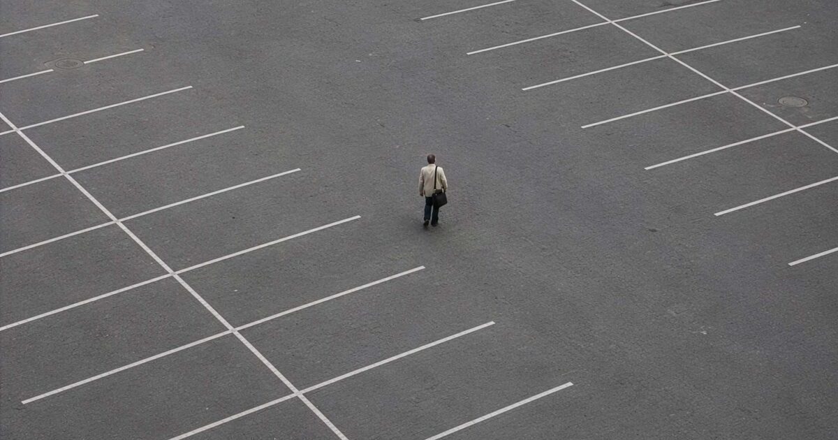 A man standing in the middle of a empty carpark